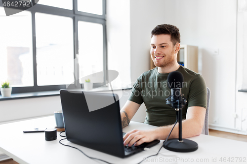 Image of man with laptop and microphone at home office