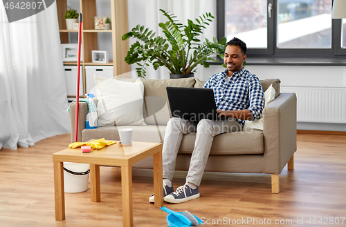 Image of man with laptop computer after home cleaning