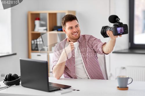 Image of male blogger with camera videoblogging at home