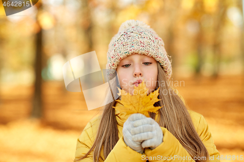 Image of portrait of girl with maple leaf at autumn park