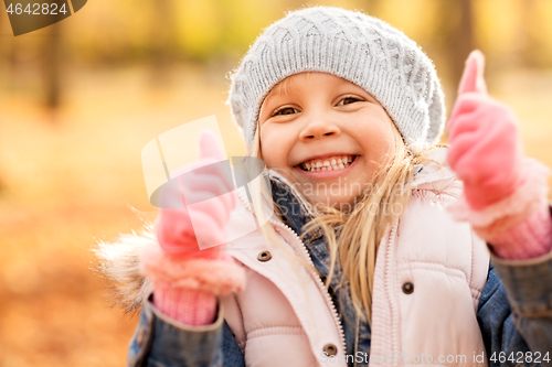 Image of happy little girl at autumn park showing thumbs up