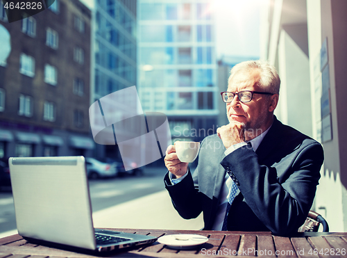 Image of senior businessman with laptop drinking coffee