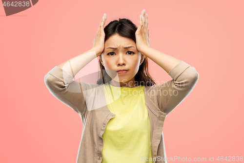 Image of stressed asian woman holding to her head