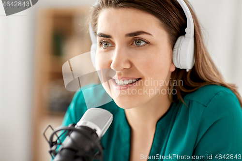 Image of woman with microphone recording podcast at studio