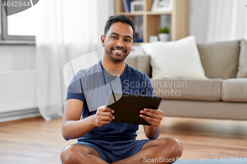 Image of indian man with tablet pc and exercise mat at home