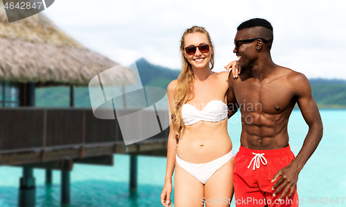 Image of mixed race couple walking along beach with friends
