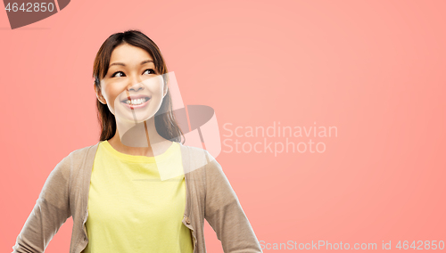 Image of happy asian woman looking up over grey background
