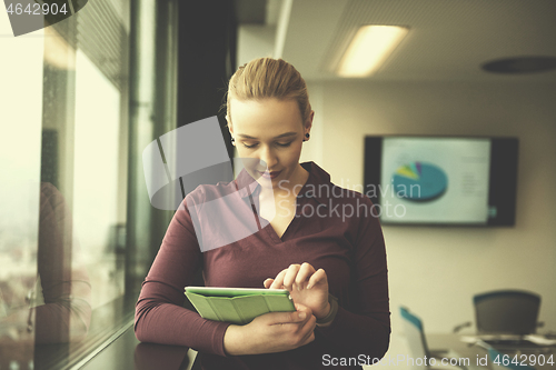 Image of blonde businesswoman working on tablet at office