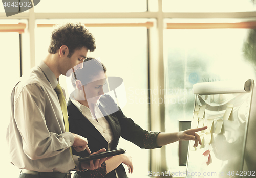 Image of young couple working on flip board at office