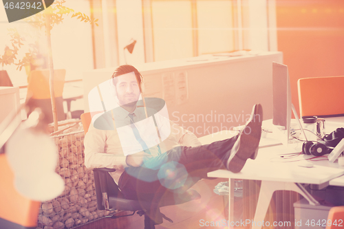 Image of relaxed young businessman first at workplace at early morning