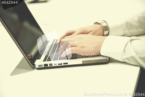 Image of hands typing on laptop at meeting