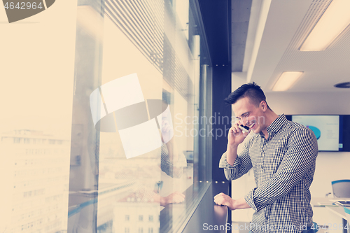 Image of young business man speaking on  smart phone at office