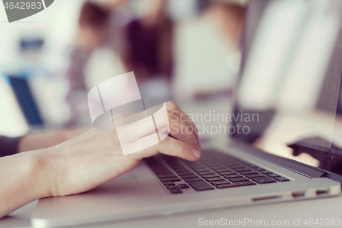 Image of close up of business womans hand typing on laptop with team on m