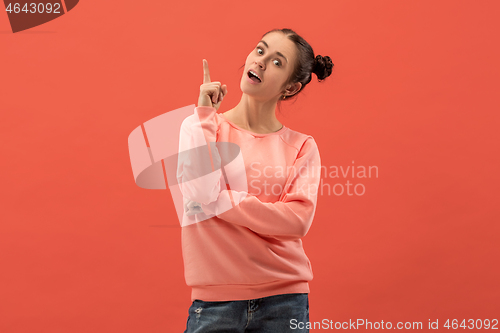 Image of The happy woman standing and smiling against coral background.