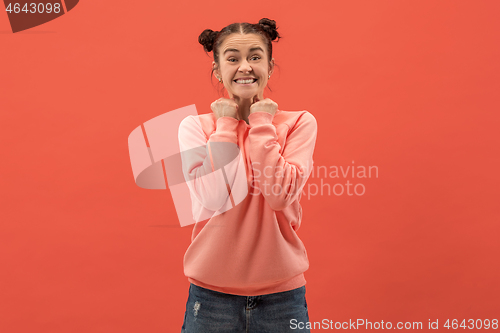 Image of The happy woman standing and smiling against coral background.