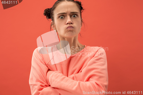 Image of Portrait of an angry woman looking at camera isolated on a coral background