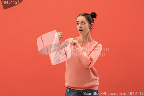 Image of The happy woman standing and smiling against coral background.