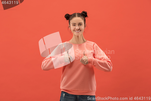 Image of The happy business woman standing and smiling against coral background.