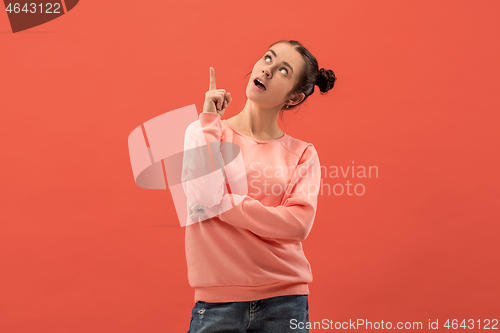 Image of The happy woman standing and smiling against coral background.