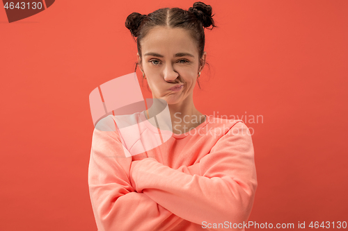 Image of Portrait of an angry woman looking at camera isolated on a coral background