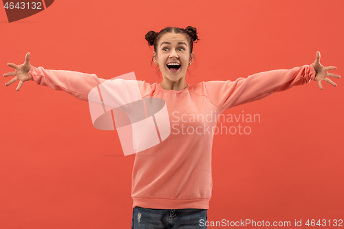 Image of The happy woman standing and smiling against coral background.
