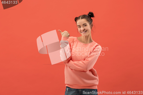 Image of The happy woman standing and smiling against coral background.