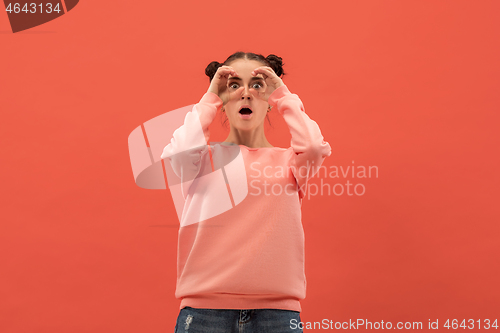 Image of Beautiful woman looking suprised isolated on coral