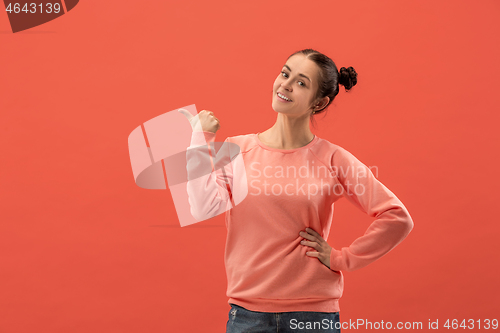 Image of The happy woman standing and smiling against coral background.