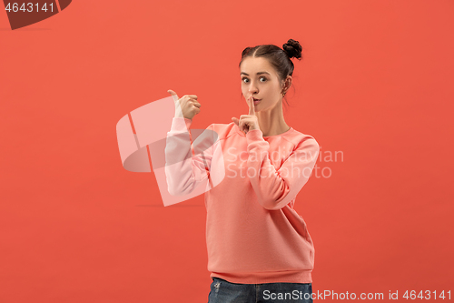 Image of The happy woman standing and smiling against coral background.