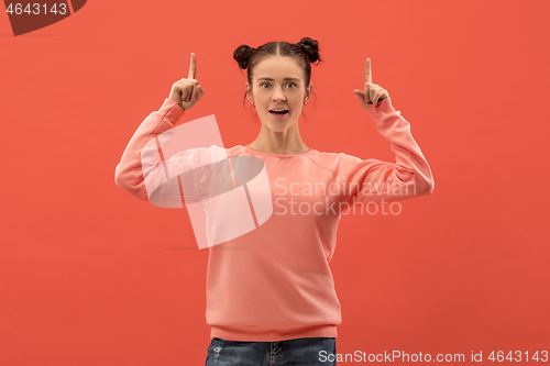 Image of The happy woman standing and smiling against coral background.