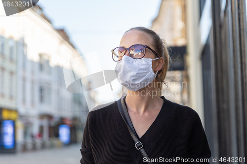 Image of COVID-19 Pandemic Coronavirus. Young girl in city street wearing face mask protective for spreading of Coronavirus Disease 2019. Close up of young woman with medical mask on face against SARS-CoV-2.