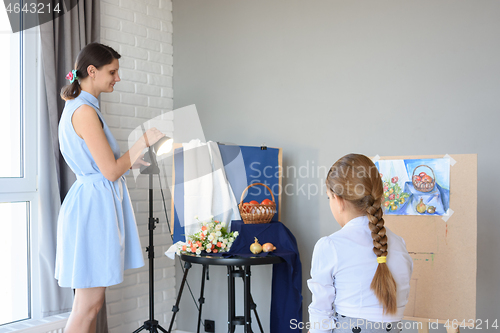 Image of An art school teacher explains to a student how to draw a still life