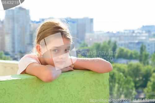 Image of Happy girl looking at the street from the balcony of the house