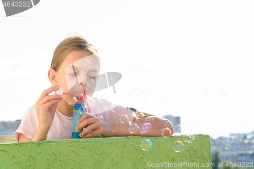 Image of Girl blows bubbles on the balcony of a high-rise building