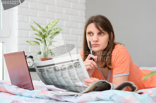 Image of Girl thinking while looking at newspaper job advertisements