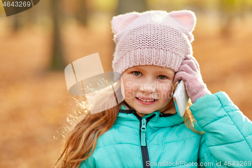 Image of happy girl calling on smartphone at autumn park