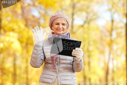 Image of senior woman with tablet computer at autumn park