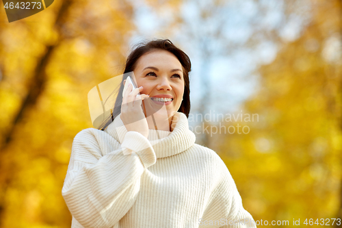 Image of woman calling on smartphone in autumn park