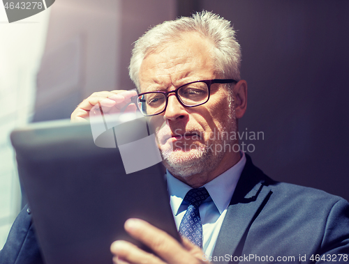 Image of senior businessman with tablet pc on city street