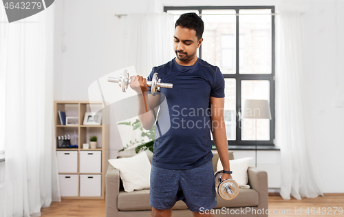 Image of indian man exercising with dumbbells at home