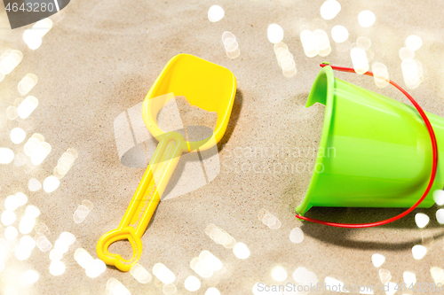 Image of close up of toy bucket and shovel on beach sand