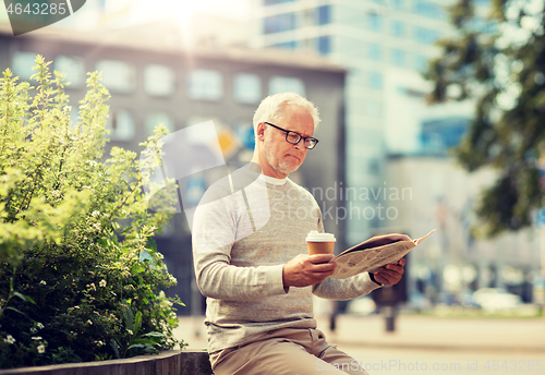 Image of senior man reading newspaper and drinking coffee