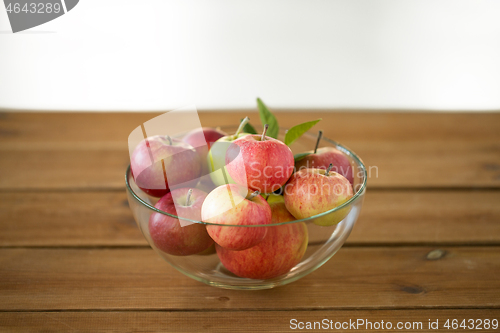 Image of ripe apples in glass bowl on wooden table