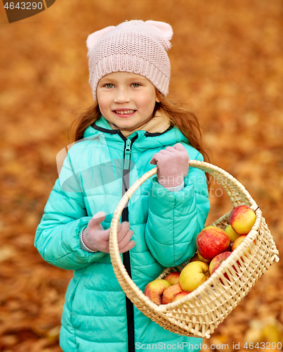 Image of girl with apples in wicker basket at autumn park