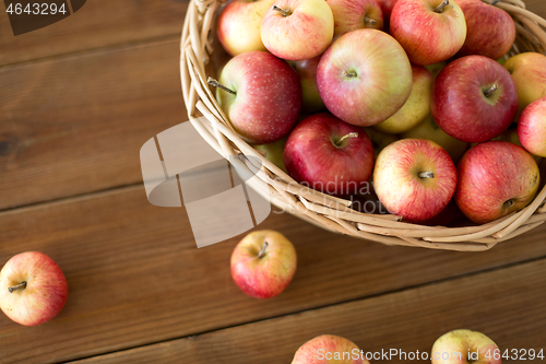 Image of ripe apples in wicker basket on wooden table