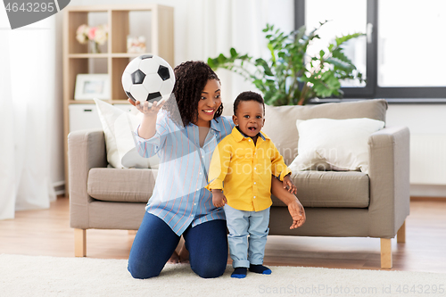 Image of mother and baby playing with soccer ball at home