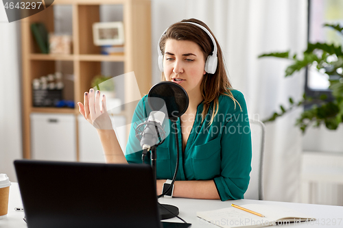 Image of woman with microphone recording podcast at studio