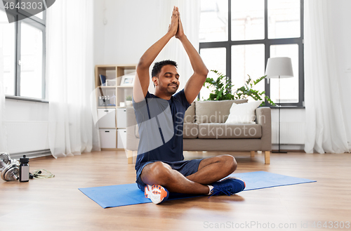 Image of indian man meditating in lotus pose at home