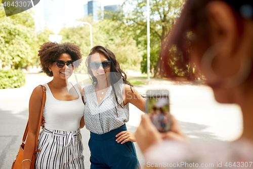 Image of woman photographing her friends in summer park