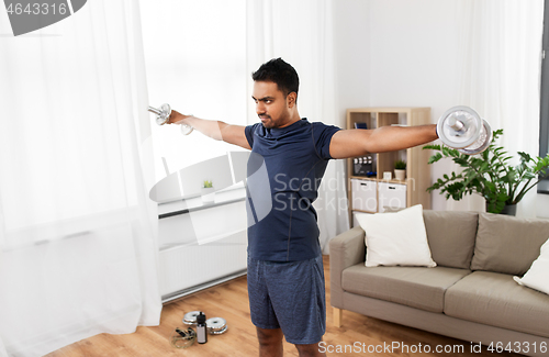Image of indian man exercising with dumbbells at home